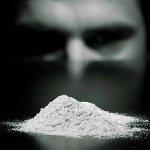 man looking at cocaine powder on the table