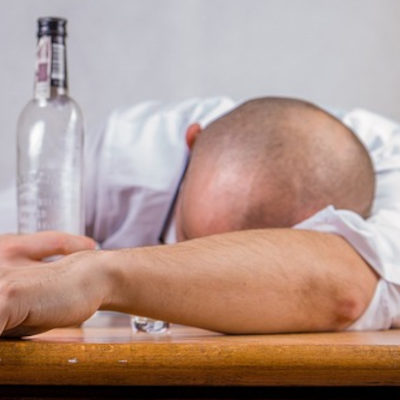 man passed out on a desk with an alcohol bottle in his hand