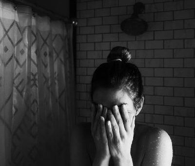 woman under the shower experiencing panic attack