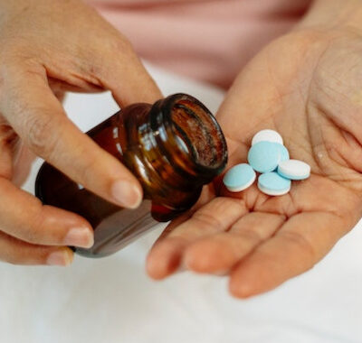 woman holding bottle and blue and white round pills
