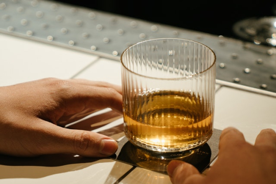 hands reaching for a glass of whiskey