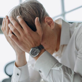 man holding his head in his hands, having hard time to concentrate