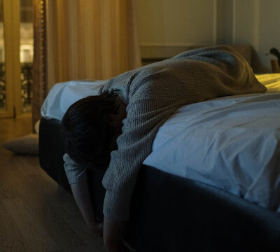 woman lying at the end of the bed with her head down