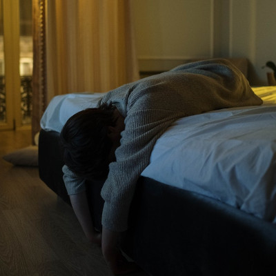 woman lying at the end of the bed with her head down
