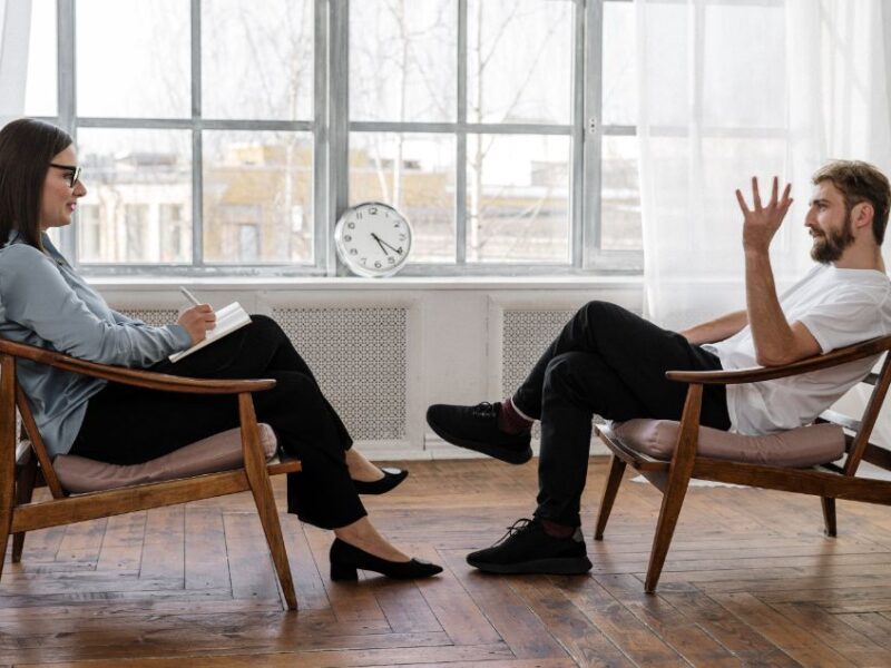 two people sitting opposed to each other having a therapy session