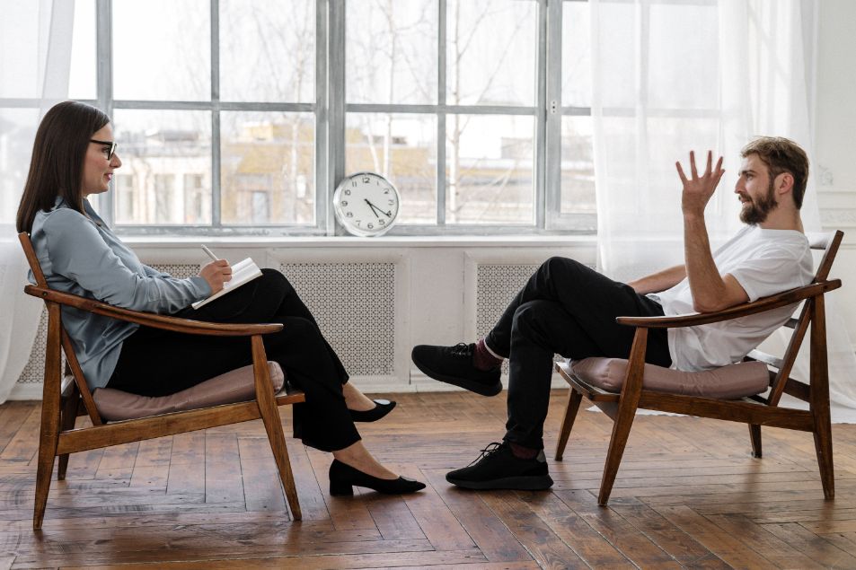 two people sitting opposed to each other having a therapy session