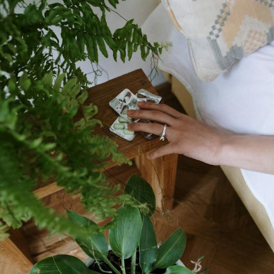 woman's hand reaching for pills that are on the table beside the bed