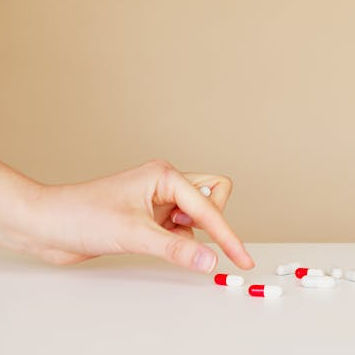 hand taking a red and white pill