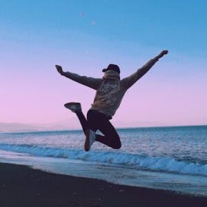 happy man jumping on the beach during sunset