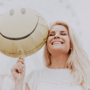 happy woman holding a smiley face balloon