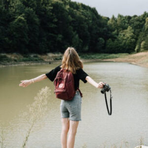 woman feeling free on her walk to the lake with her camera