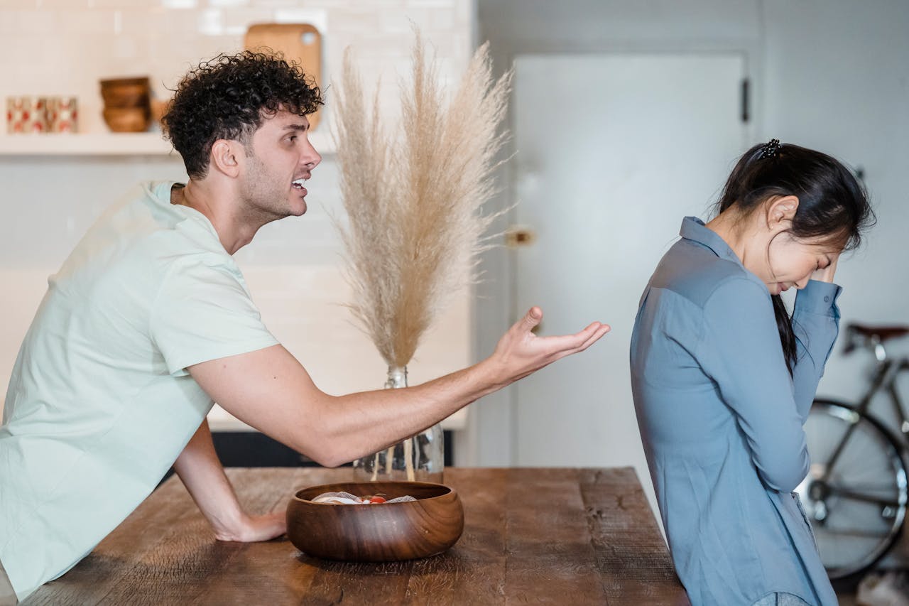 In a kitchen, a man and woman are visibly arguing, with expressions of frustration and disagreement on their faces