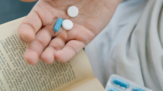 student with book in one hand and drugs in the other
