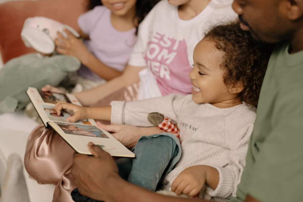 Photograph of a Child Looking at a Photo Album with Her Family