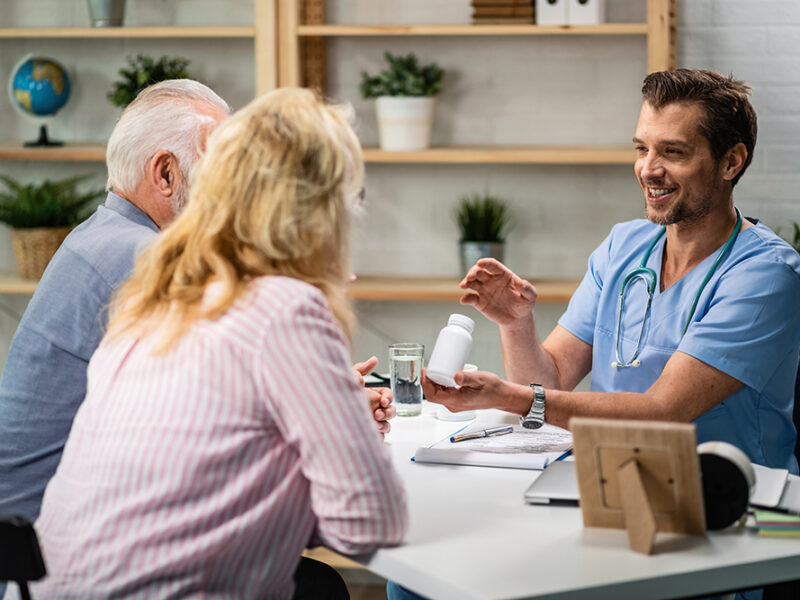 Healthcare professional consulting with senior couple in a medical office