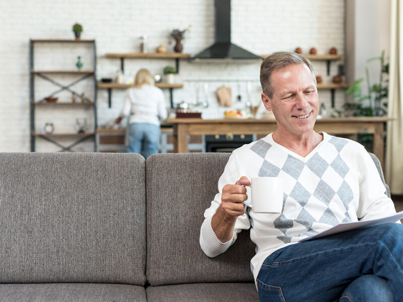 Man sitting on a couch reading with a coffee mug in a living room