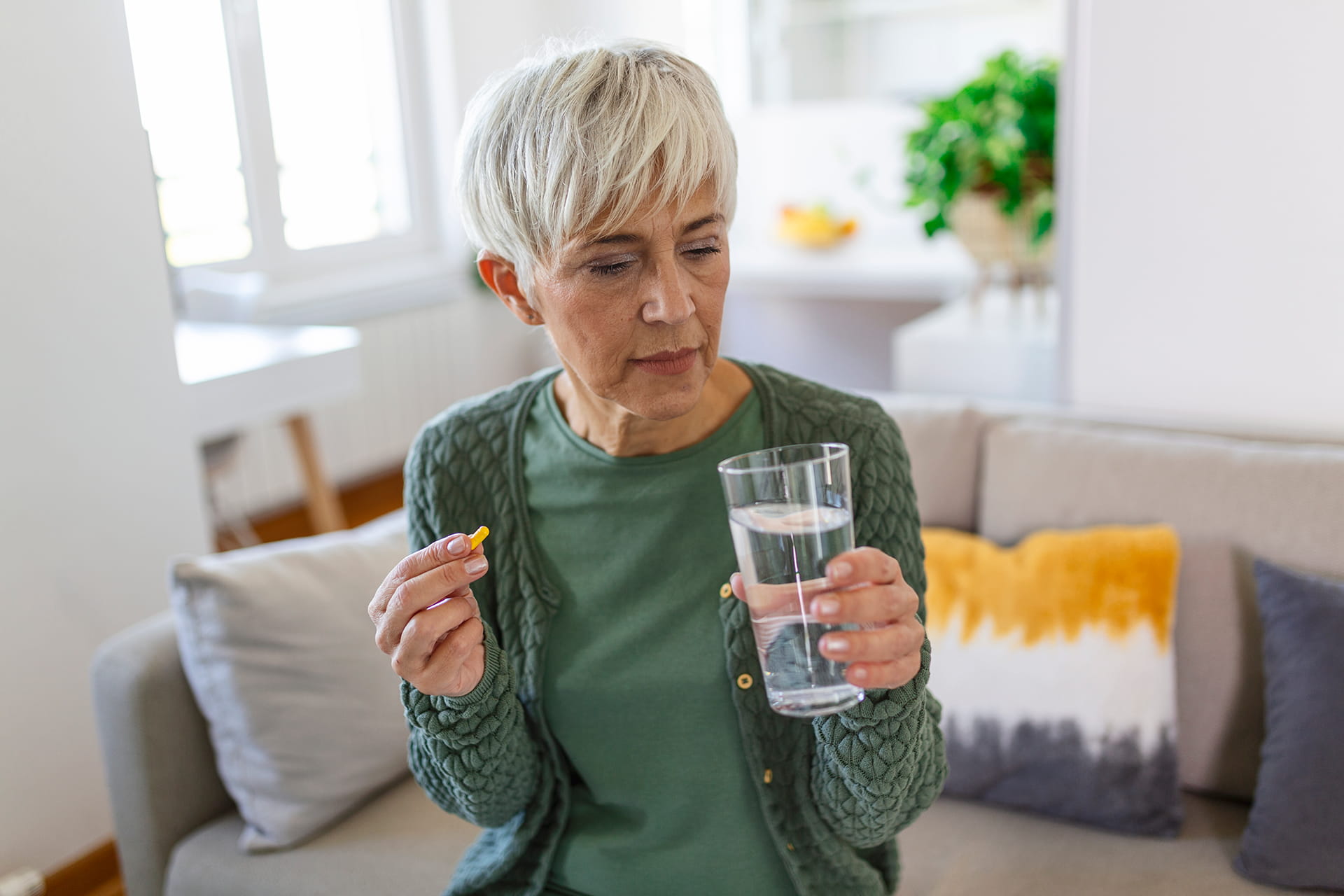 senior woman takes pill with glass water hand