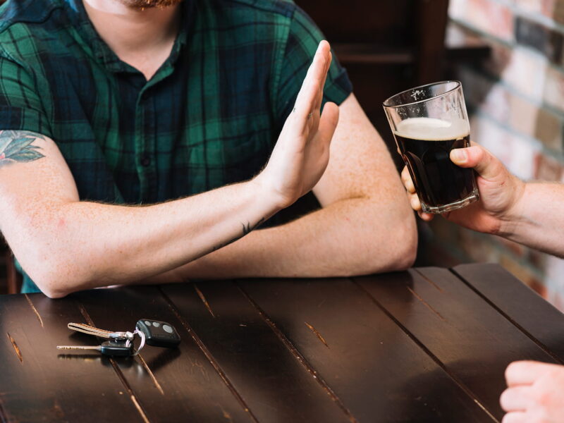 Man refusing glass of rum offered by his friend.