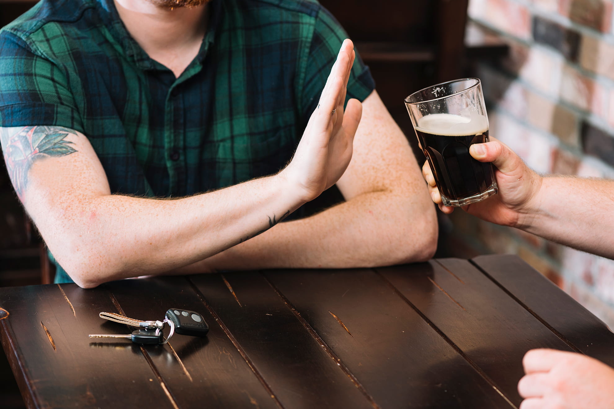 Man refusing glass of rum offered by his friend.
