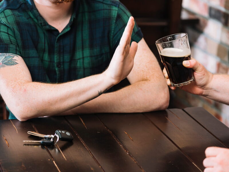 Man refusing glass of rum offered by his friend