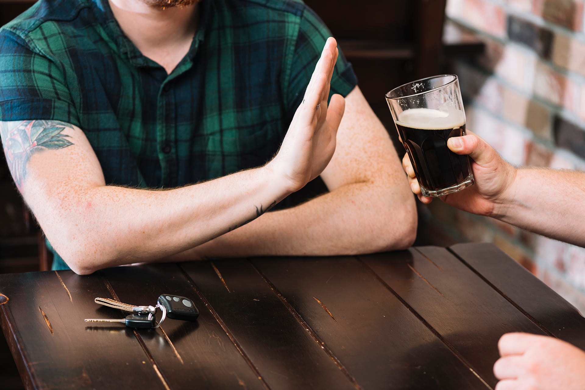 Man refusing glass of rum offered by his friend
